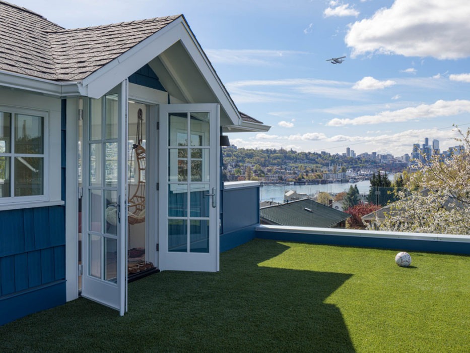 The roof deck with AstroTurf and glass panel railing overlooking lake Union and Seattle on the third story addition of the Urban Farmhouse in Wallingford.