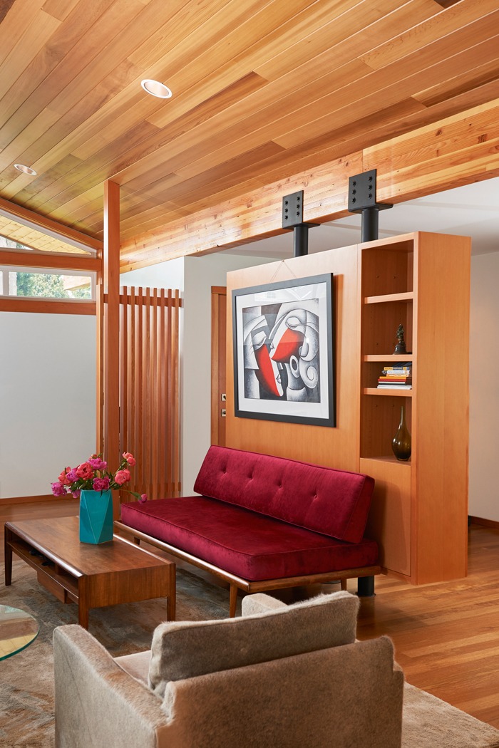 Living room in the Kirkland seattle Mid Century Remodel with exposed beam and wood ceiling, custom interior screen, and floating built in bookshelf wall.