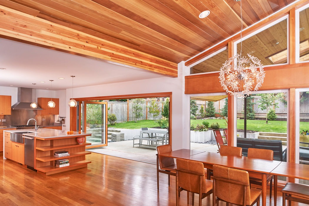 Kirkland seattle Mid Century Modern Remodel open kitchen and dining room, vaulted exposed wood ceiling, custom kitchen island, folding door onto patio.